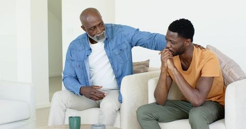 Father Offering Support to Son on Couch with Coffee