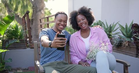 Couple Smiling and Taking Selfie Outdoors Holding Flowers