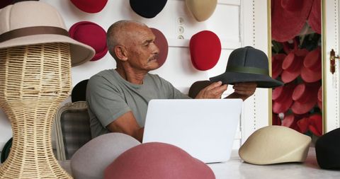 Senior man evaluating hat in fashion studio
