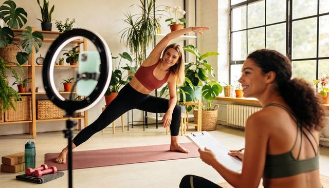 Yoga instructor leading home studio side stretch during live online fitness class