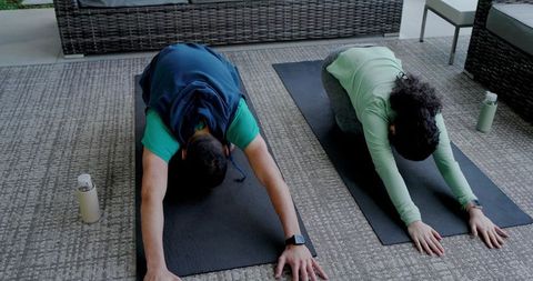 Asian Friends Practicing Child Pose on Patio with Yoga Mats