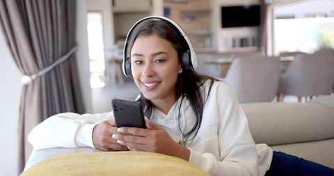 Woman Relaxing on Couch with Headphones and Smartphone at Home