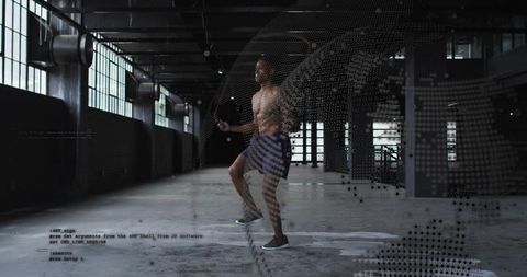 Shirtless athlete jumping rope in industrial warehouse with digital data overlay