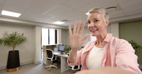Senior woman waving during office video call