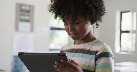 African American schoolboy using tablet in classroom learning and focusing on screen engagement
