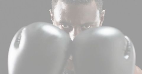 Intense boxer holding gloves close to camera, focused eyes and fierce determination