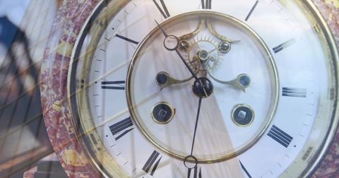 Antique mantel clock reflecting storefront glass, marbled bezel and exposed brass movement
