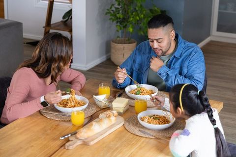 Family sharing homemade spaghetti dinner around cozy wooden dining table