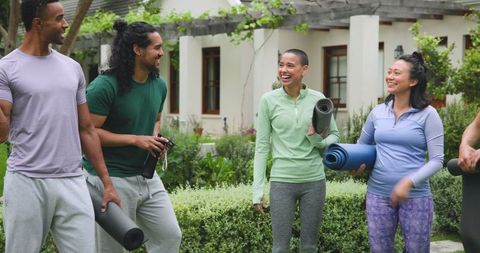 Cheerful group of friends holding yoga mats outdoors