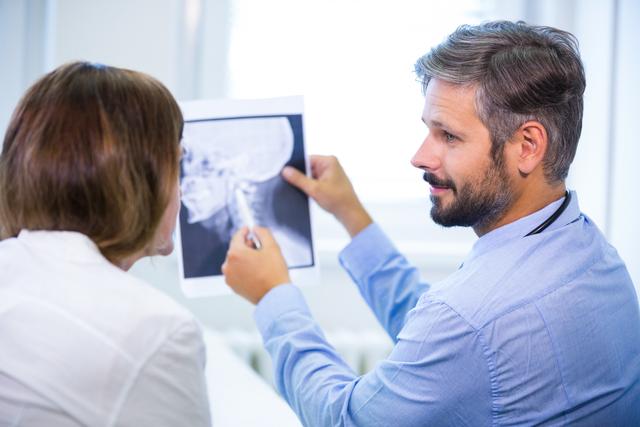 Doctor explaining x-ray results to patient in hospital setting. Useful for illustrating medical consultations, healthcare services, patient-doctor interactions, and radiology discussions. Ideal for medical websites, health blogs, and educational materials on medical diagnostics.