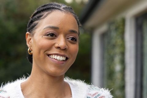 African american woman smiling outdoors wearing fuzzy sweater, gold hoops and nose stud