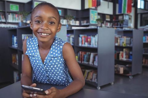 Smiling African American Girl Using Smartphone in Library