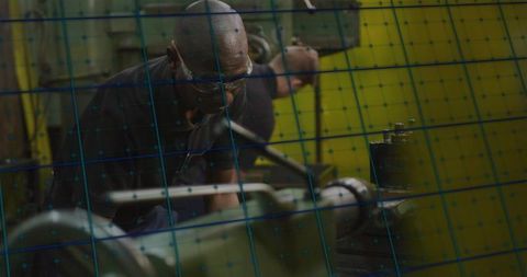 Technician using lathe with safety glasses in industrial workshop