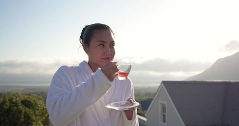Asian woman enjoying morning tea on rooftop balcony with mountain view