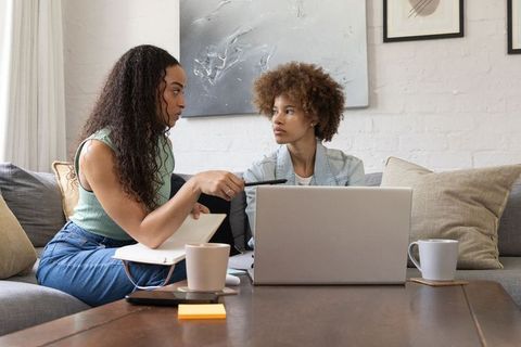 African american women studying on sofa with laptop and notebook for remote learning