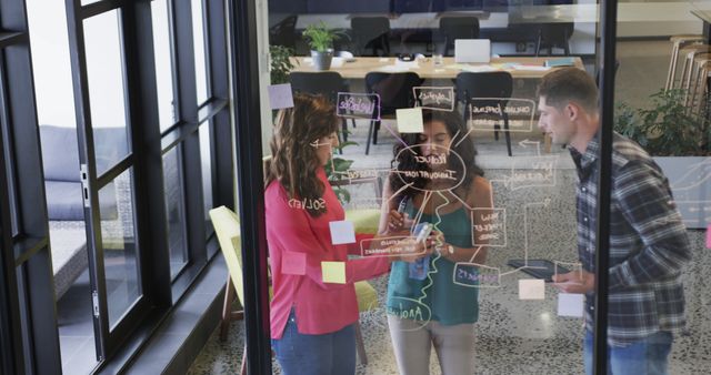 Team brainstorming with sticky notes on glass in modern office - Download Free Stock Images Pikwizard.com