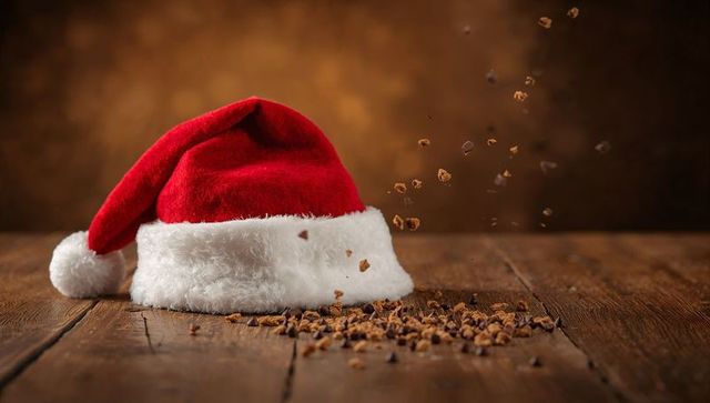 Red Santa hat with falling cookie crumbs on rustic wooden tabletop holiday still life