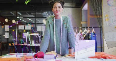 Young fashion designer organizing fabrics in modern studio with laptop and garment rack