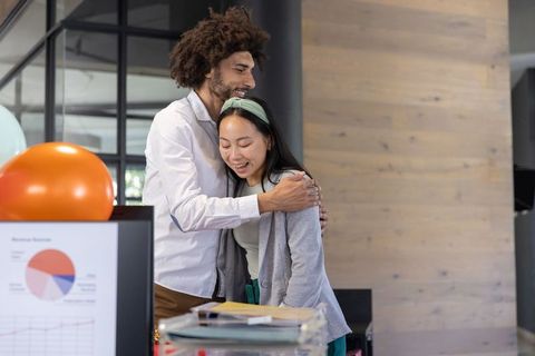 Diverse Coworkers Embracing in Modern Office with Charts