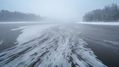 Tug navigating icy river channel cutting through slush and fog creating turbulent wake video