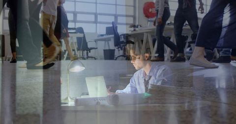 Focused professional working late at open-plan office with blueprints and reflections