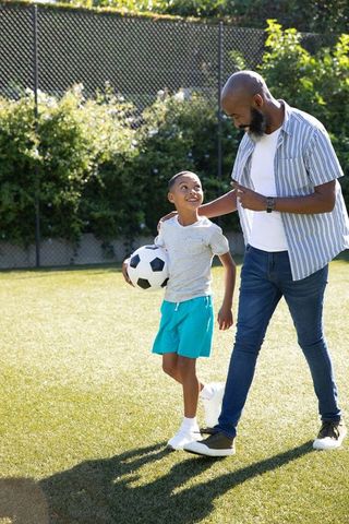 Father Bonding with Son on Soccer Field Sharing Moment