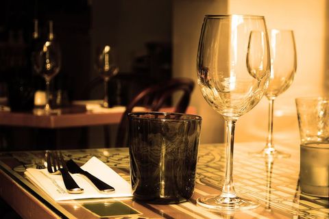 Restaurant Table Glowing with Warm Light Featuring Wine Glasses, Cutlery and Glassware