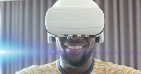 Smiling man wearing white vr headset experiencing immersive virtual world in home interior