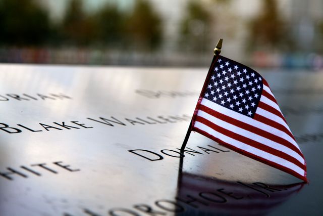 American flag placed at memorial site honoring victims. Represents patriotism, remembrance, and tribute. Ideal for use in content related to national remembrance events, honoring fallen victims, and patriotic ceremonies.