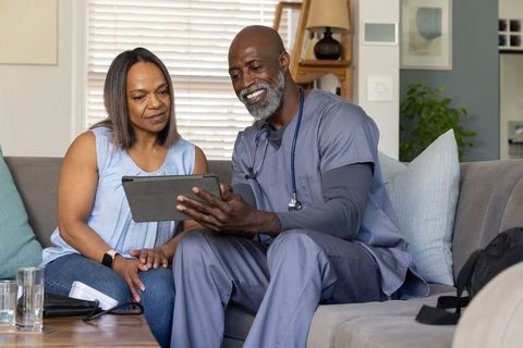 African american clinician conducting home visit consultation using tablet and stethoscope
