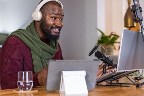 African american podcaster recording in cozy home office with headphones and microphone