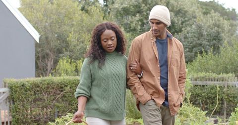 African American Woman Walking with Partner Through Backyard Garden Holding Wicker Basket