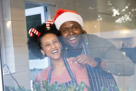 Smiling african american couple wearing santa hat and candy cane headband celebrating holidays
