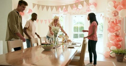Diverse friends setting up festive party table at home celebration