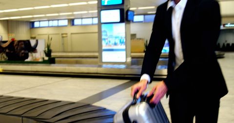 Businessman Taking Luggage at Airport Baggage Carousel