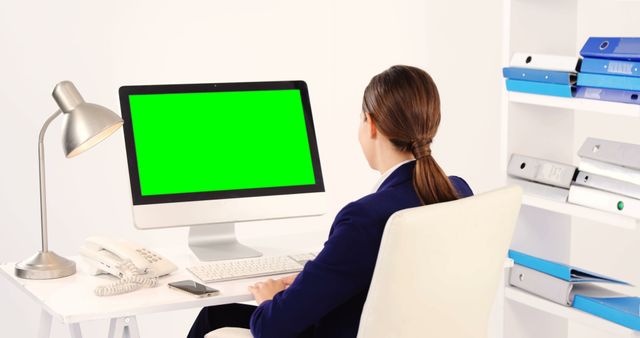 Caucasian businesswoman using computer with green screen at desk with copy space. Business, finance and technology concept, unaltered.