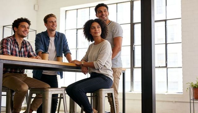 Young diverse team collaborating around high table in bright modern coworking loft