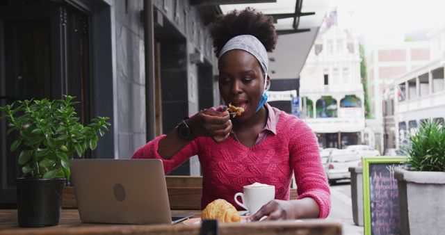 Young woman working on laptop while eating breakfast at a cafe - Download Free Stock Images Pikwizard.com