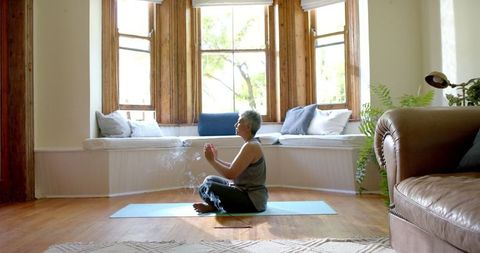 Senior Woman Practicing Meditation on Yoga Mat in Cozy Home