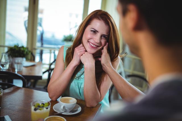 Couple interacting while having coffee in cafÃ©