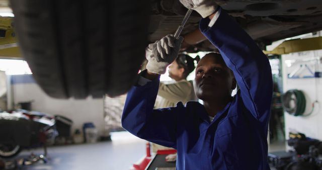 Image of african american female car mechanic repairing car. working in car repair shop and running small feminine business concept.