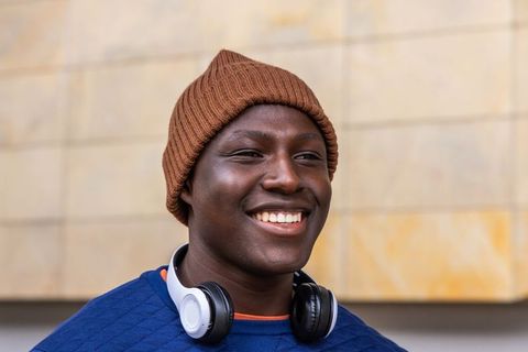 African american man smiling wearing brown beanie headphones urban lifestyle portrait