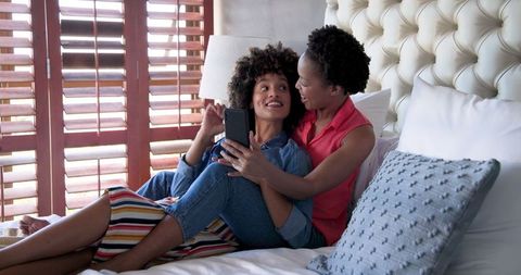 Diverse Female Couple Enjoying Video Call Together on Bed