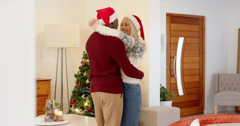 Romantic couple hugging by christmas tree in festive living room