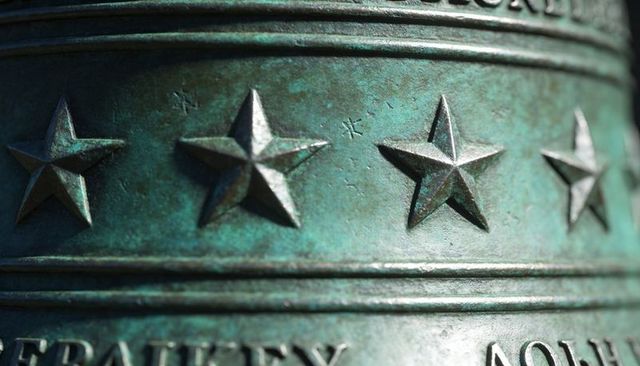 Cast bell featuring raised five-pointed stars and verdigris patina close-up texture