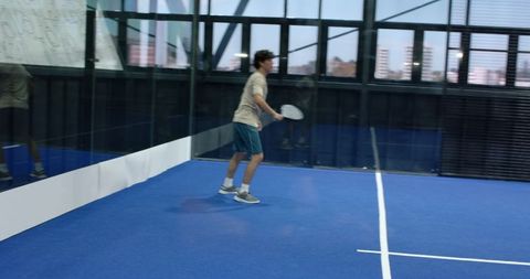 Man holding racket on blue padel court