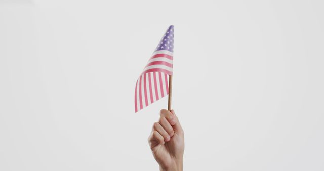 Close up of hand holding national flag of usa on white background with copy space. Patriotism, memorial day and celebration concept.
