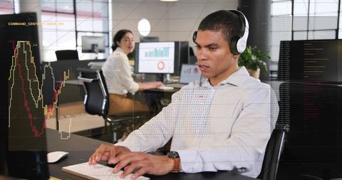 Focused professional wearing headset typing on keyboard with analytics and code on screens