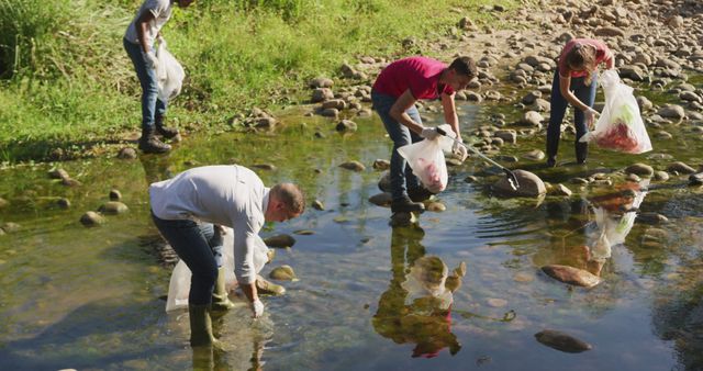 A multi-ethnic group of conservation volunteers cleaning up a river on a sunny day in the countryside, picking up rubbish. Ecology and social responsibility in a rural environment.