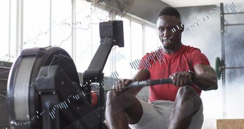 Focused male athlete rowing on ergometer for intense indoor cardio and strength training